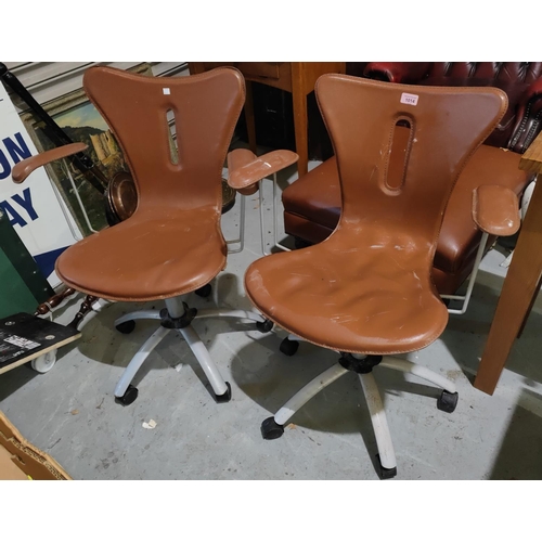 1014 - A modern pair of designer swivel armchairs with tan coloured seats and backs