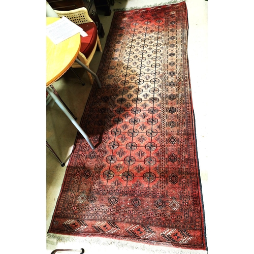 929 - A Middle Eastern rust ground long rug with three lines of medallions, multiple borders etc 296 x 105... 