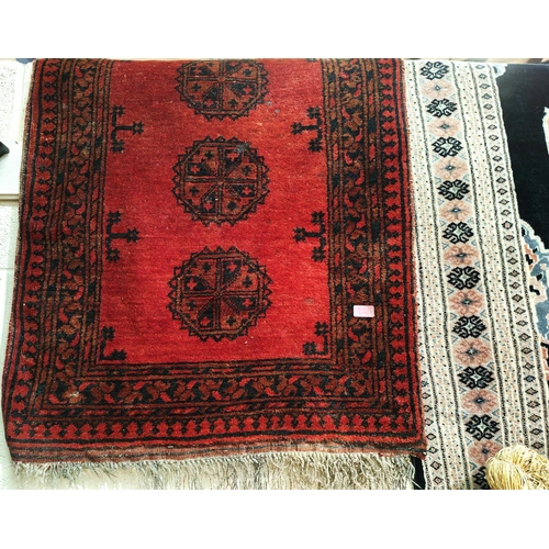 929 - A Middle Eastern rust ground long rug with three lines of medallions, multiple borders etc 296 x 105... 