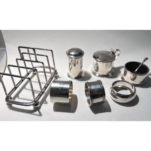 774 - Three hallmarked silver napkin rings; and Art Deco cruet; a 1930's silver plated toast rack