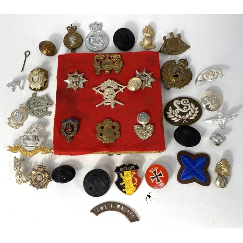 310 - A small selection of military badges attached to wooden board and a larger selection of loose