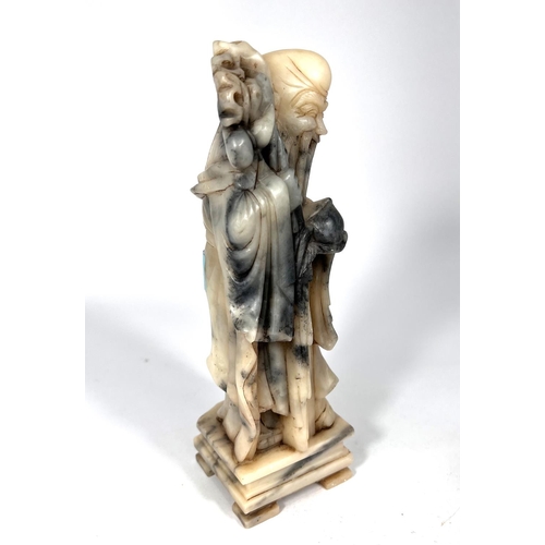 393 - A mottled grey and cream soapstone depicting an Immortal holding a peach and a staff height 25cm