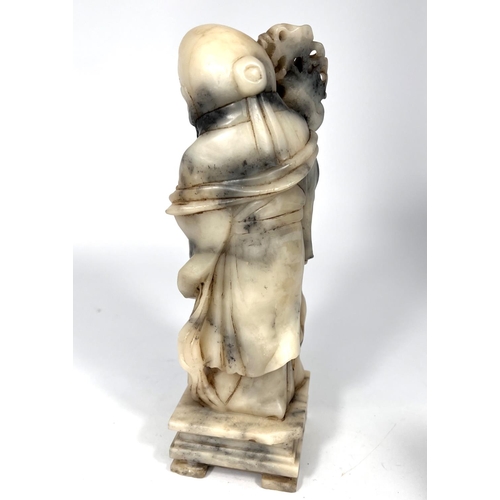 393 - A mottled grey and cream soapstone depicting an Immortal holding a peach and a staff height 25cm