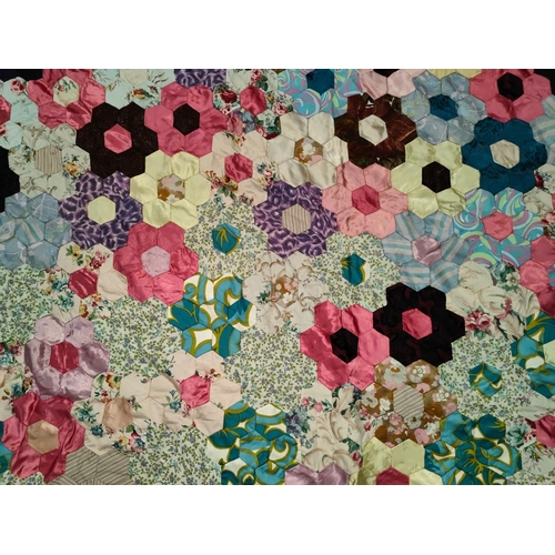 62 - A large vintage patchwork quilt made up of hexagonal pieces in a floral shape, 215x200 cm 