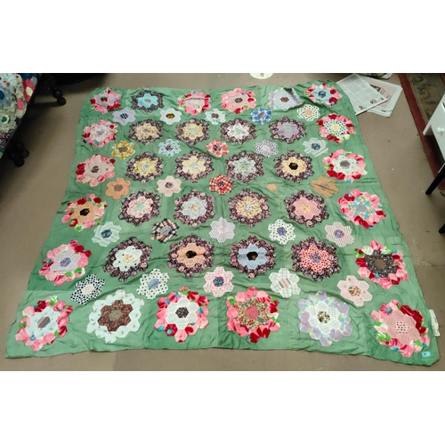 63 - A large patch work quilt (unbacked) with green material with hexagonal pieces in floral shapes, 205x... 