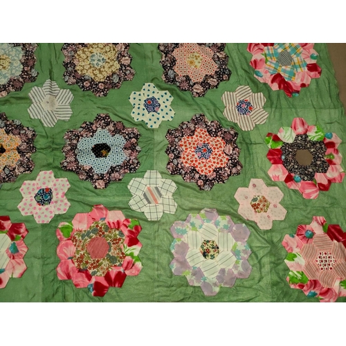 63 - A large patch work quilt (unbacked) with green material with hexagonal pieces in floral shapes, 205x... 