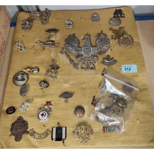 312 - A selection of military badges and buttons attached to a board