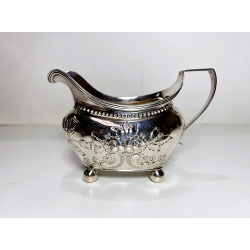 623A - A Georgian hallmarked silver sauce boat with embossed floral and scroll decoration on four ball feet... 