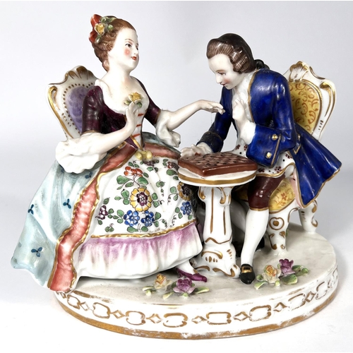 592 - A porcelain group of lady and gentleman in 18th century dress playing chess, in the Chelsea manner w... 