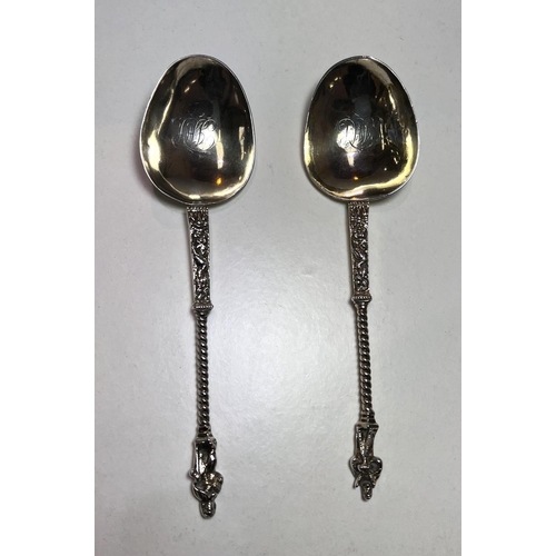 620 - A pair of continental white metal apostle top anointing spoons with monogrammed and gilded bowls.