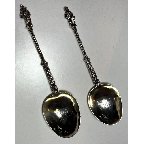 620 - A pair of continental white metal apostle top anointing spoons with monogrammed and gilded bowls.