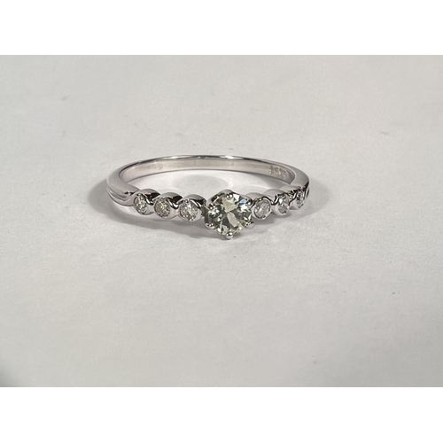 765 - An 18 carat hallmarked white gold ring set with a central clear stone, 23 small diamonds to each sho... 