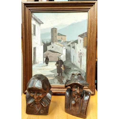 40A - A small oil on canvas painting of a continental street scene, two Bavarian style carved wooden heads