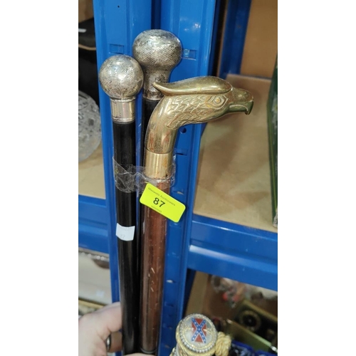 87 - An ebony walking stick with silver finial; another similar, both 1900; another stick with eagle fini... 