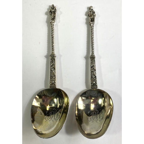 620 - A pair of continental white metal apostle top anointing spoons with monogrammed and gilded bowls.