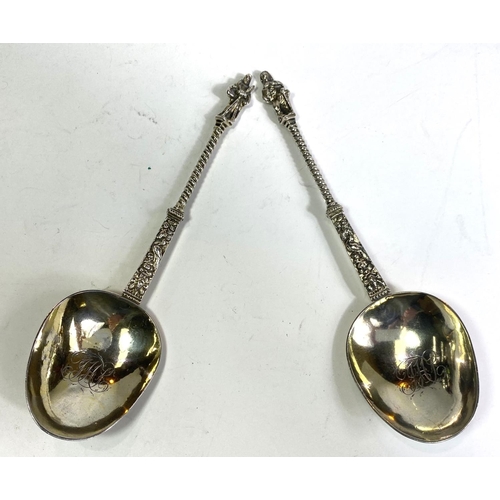 620 - A pair of continental white metal apostle top anointing spoons with monogrammed and gilded bowls.