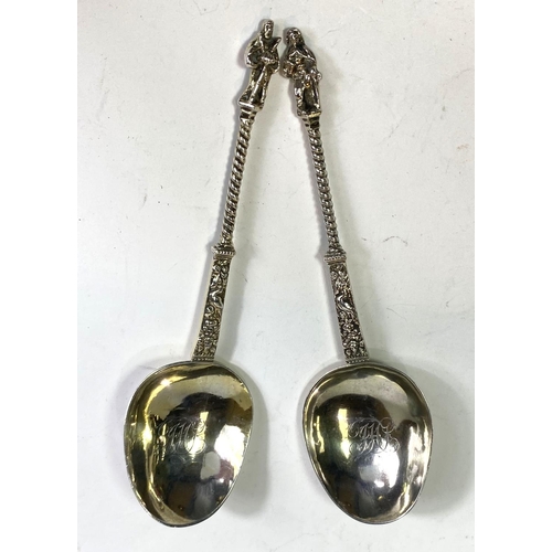 620 - A pair of continental white metal apostle top anointing spoons with monogrammed and gilded bowls.