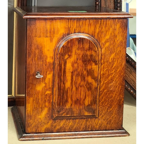 12 - An 1930's oak smokers cabinet with panelled door and hinged lid, jar to the interior; two black and ... 