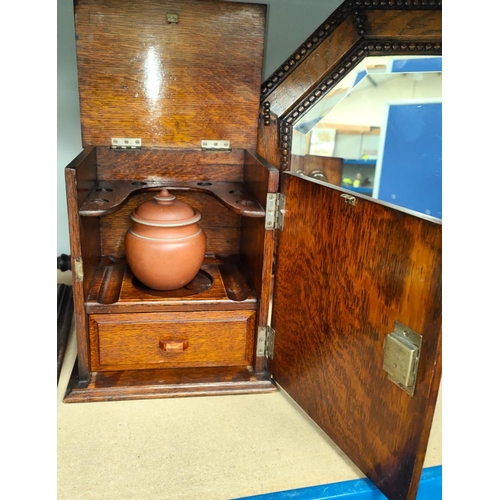 12 - An 1930's oak smokers cabinet with panelled door and hinged lid, jar to the interior; two black and ... 