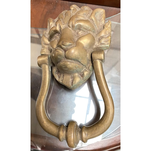 10A - A brass lions head door knocker and a brass depiction of Greek scholar reading