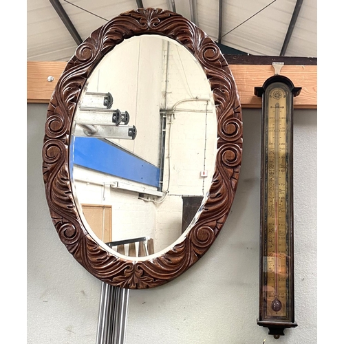 42 - A wall mirror in carved oak oval frame; a pair of raffia seat stools; an aneroid barometer