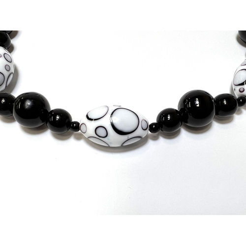 716 - VENICE STYLE, a glass bead necklace in black and white with silver clasp, 64cm; a polished bead neck... 