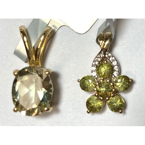 723 - A flower head pendant set with green stones; a pendant set with a light blue oval stone, both stampe... 