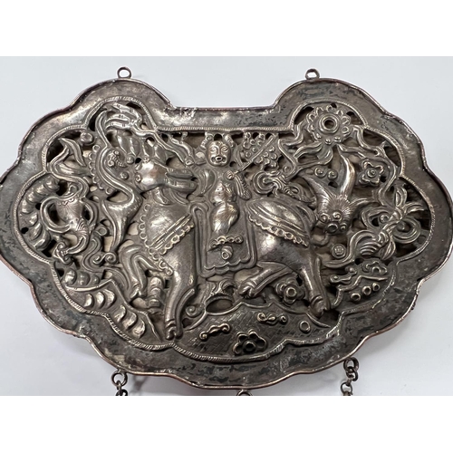 391 - A Chinese white metal large pendant with pierced decoration of person riding dragon length 17cm