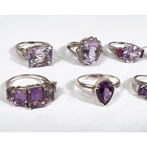 621 - Eight silver rings in a variety of designs, each set with 1 or more amethyst coloured stones, 39.4gm