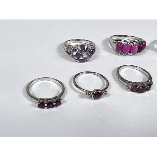 627 - Eight silver rings in a variety of settings, each with pink/ amethyst coloured stones, 26.9gm