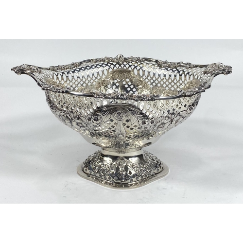 697 - An elongated oval bowl on pedestal with scroll and flower border, extensively pierced body with flor... 