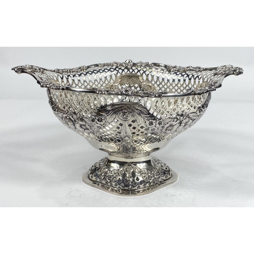 697 - An elongated oval bowl on pedestal with scroll and flower border, extensively pierced body with flor... 