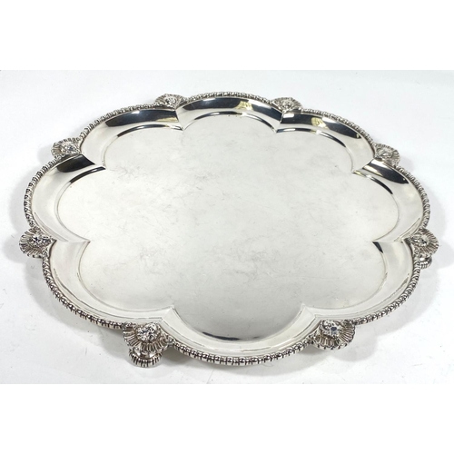 702 - A hallmarked silver scalloped circular tray with raised beaded border and sunburst facemask mounts, ... 