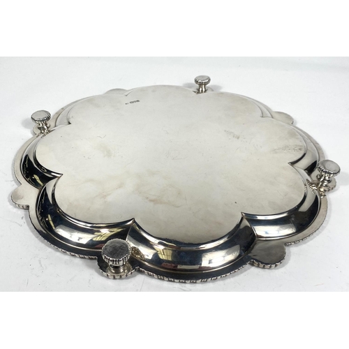 702 - A hallmarked silver scalloped circular tray with raised beaded border and sunburst facemask mounts, ... 