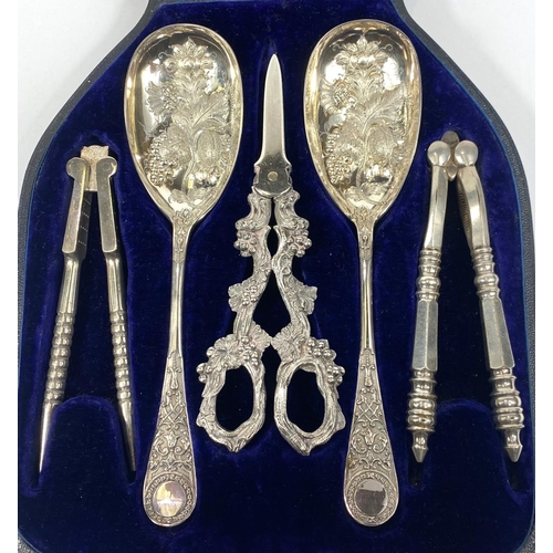 712 - An ornate set comprising berry spoons, nutcrackers and grape scissors, cased; a hallmarked silver ch... 