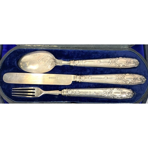 712 - An ornate set comprising berry spoons, nutcrackers and grape scissors, cased; a hallmarked silver ch... 