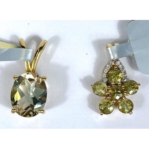 723 - A flower head pendant set with green stones; a pendant set with a light blue oval stone, both stampe... 