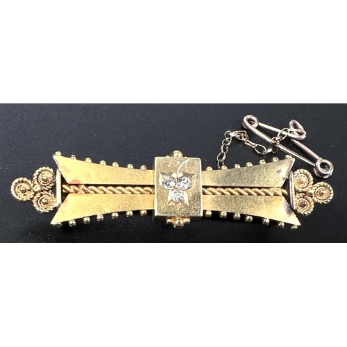 749 - A yellow metal bar brooch set with 3 diamonds and with filigree decoration, stamped 15ct, 4.7gm