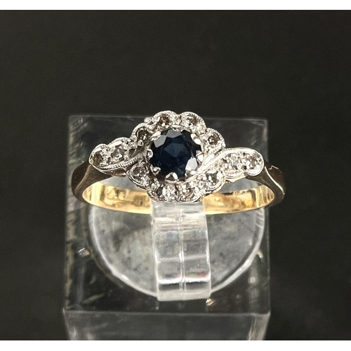 751 - An 18ct hallmarked gold ring with central sapphire and small diamonds in crossover form