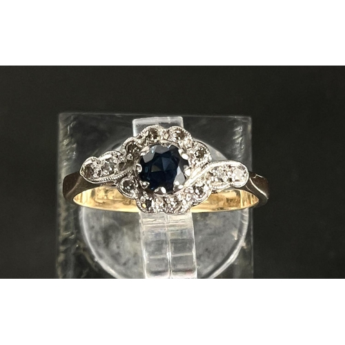 751 - An 18ct hallmarked gold ring with central sapphire and small diamonds in crossover form