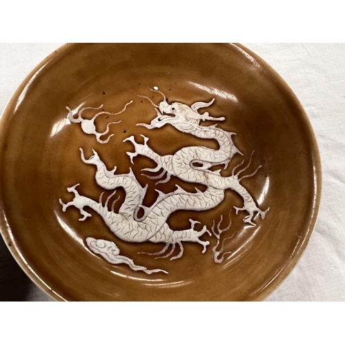 364 - A 19th century oriental pale green glazed dish and a Chinese round glazed dish with relief dragon to... 