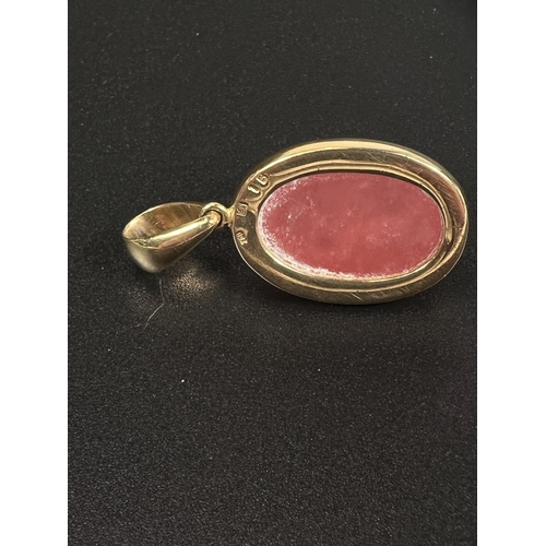 694 - A pendant set cabochon cut pink stone, the yellow metal surround, stamped '750'