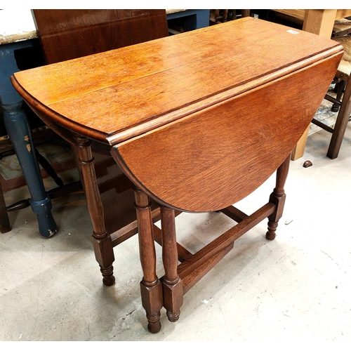 847 - An oak dining table with oval drop leaf top, on turned legs and three dining chairs.