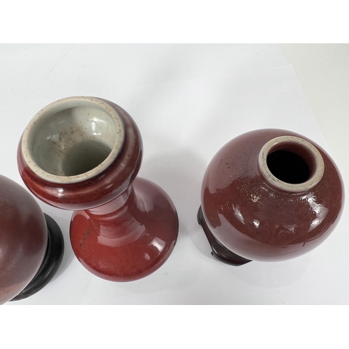 403 - Three Chinese red glazed vases of various shapes and sizes all with hard wood stands, largest, 16cm,... 