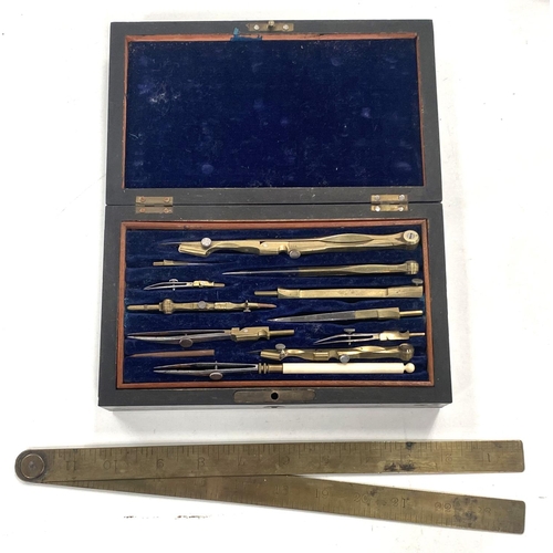 106 - A cased brass drawing set with fold out brass ruler