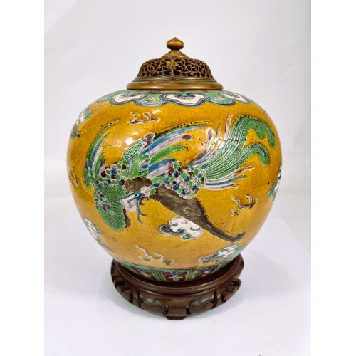 396 - A Chinese ginger jar shaped vase with an exotic bird and dragon in polychrome against a mustard glaz...