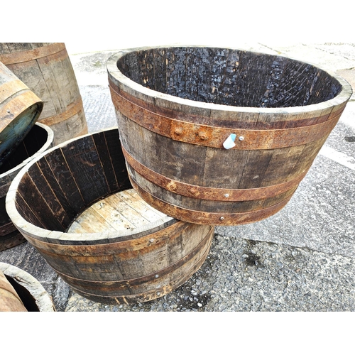 1002 - Two wooden metal bound barrel planters, diameter 61cm & 71cm