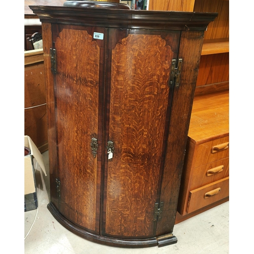 859 - A Georgian oak bow front corner cupboard with mahogany cross banding