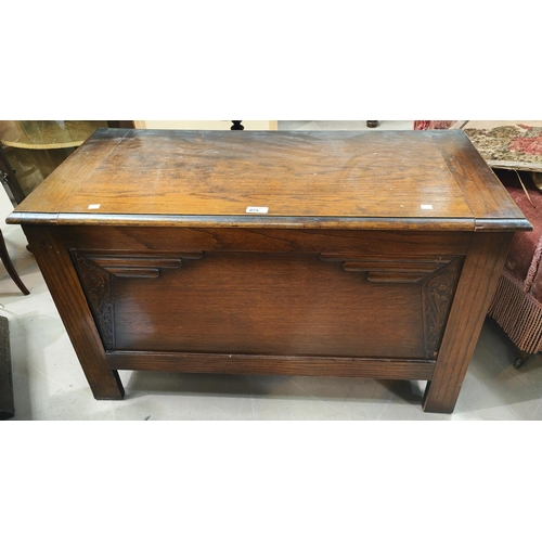 875 - A 1930's oak blanket box with hinged lid and relief decoration to the front