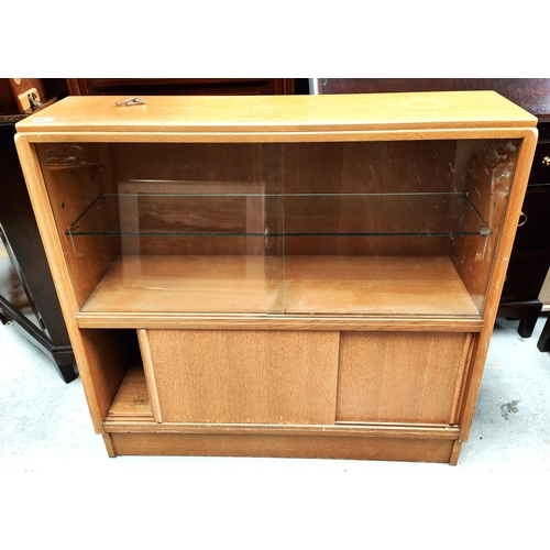 965 - A mid 20th century light oak bookcase with sliding glass doors above and sliding wooden doors below,... 